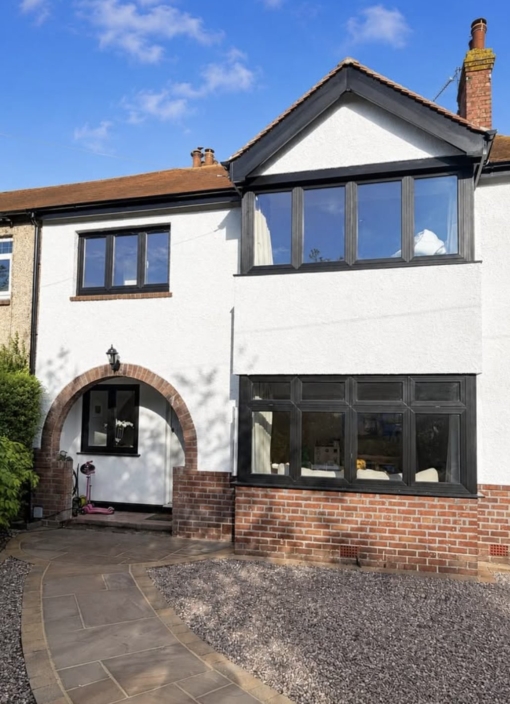Render finished down to a retained brick plinth with black window frames
